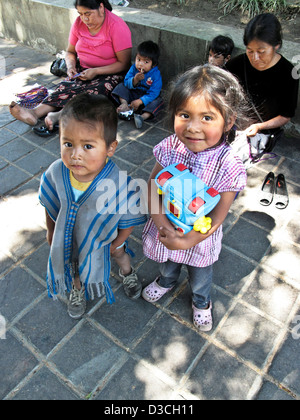 Magnifique petit garçon indien indigène mexicain avec légèrement plus anciens sister holding jouets en plastique dans Zocalo Oaxaca de Juarez, Mexique Banque D'Images