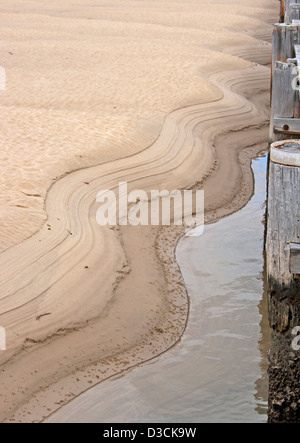 Robe de décoration naturelle faite par l'eau dans le sable au bord de l'eau à côté de la jetée de postes Banque D'Images