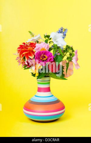 Bouquet d'été à rayures en vase sur fond jaune Banque D'Images