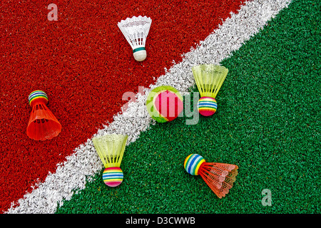 Badminton volants colorés et balle de tennis, placé sur le terrain synthétique. Banque D'Images
