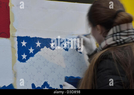 Les jeunes gens du Kosovo sur les drapeaux international peinture sculpture extérieure par Fisnik Ismajli composé de 3 mètres de haut, la lecture des lettres de métal "nouveau né" en préparation de la célébration de la Journée de l'indépendance, Pristina, Kosovo, le samedi 16 février, 2013. Le Kosovo a déclaré son indépendance en 2008 et célébrera son cinquième anniversaire le dimanche 17 février, 2013. Banque D'Images