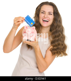 Happy young woman putting carte de crédit dans piggy bank Banque D'Images