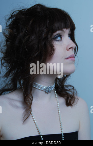 Un gros plan d'une jeune femme blanche modèle avec cheveux bruns portant des bijoux en cristal et perles dans un salon de beauté et studio Banque D'Images