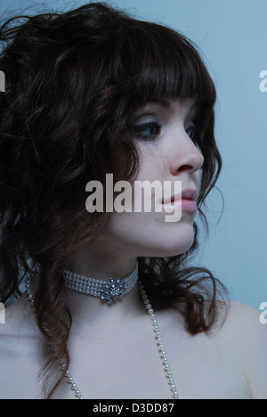 Un gros plan d'une jeune femme blanche modèle avec cheveux bruns portant des bijoux en cristal et perles dans un salon de beauté et studio Banque D'Images