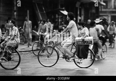 Phnom Penh, Cambodge : une femme porte une nouvelle radio accueil sur l'arrière d'un vélo. Banque D'Images