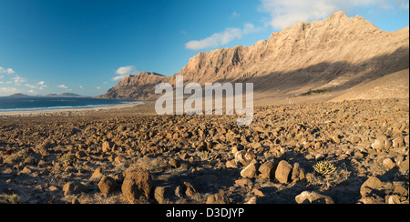 Malpais (terrain accidenté ou avec badlands gommage à sec) en face de la falaise de Famara et plage de Caleta de Famara, Lanzarote Banque D'Images