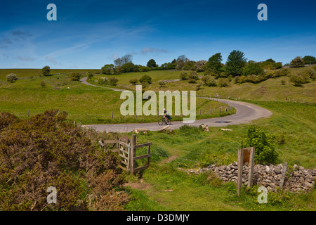 Un cycliste sur les collines de Mendip passant l'entrée de la réserve naturelle de Warren Ubley, Somerset, England, UK Banque D'Images