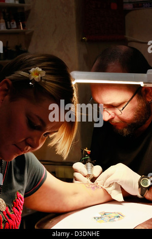 Un tatoueur d'appliquer son art sur la main d'une femme Banque D'Images