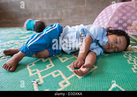 Fang, en Thaïlande, une petite fille fait une sieste sur le plancher Banque D'Images