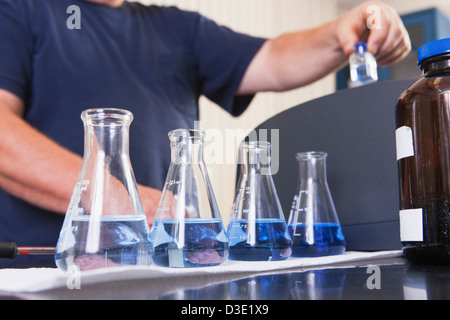 Ingénieur avec bouteilles d'échantillons de solution indigo et de l'eau ozonée et le flacon dans la main pour l'analyse en usine de traitement de l'eau Banque D'Images