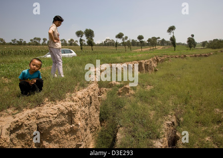 MAHUANGTOU SHANG VILLAGE, province de Shanxi, Chine - AOÛT 2007 : Un paysan et son fils inspecter l'affaissement causé par l'exploitation minière incontrôlée Banque D'Images