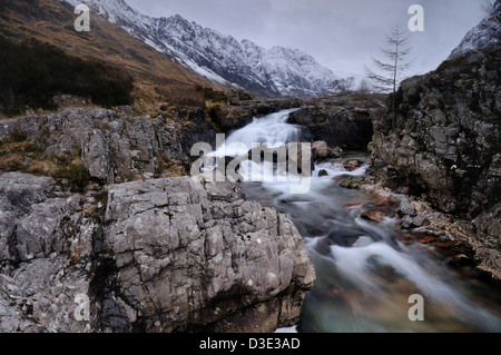 Rocky section de la rivière Coe, Glencoe, l'Écosse, avec l'Aonach Eagach couvertes de neige s'élevant au-dessus de la crête Banque D'Images