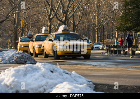 La ville de New York taxi jaune alignés et partager la route avec les coureurs sur la route de l'est à New York City's Central Park Banque D'Images