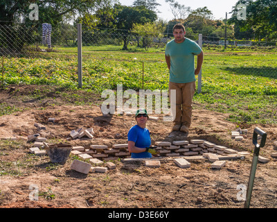 Deux volontaires internationaux contribuent à construire une maison pour les nécessiteux parrainé par Habitat pour l'humanité le Paraguay. Banque D'Images