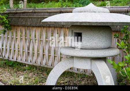 Jardin paysage japonais détail avec maru-yukimi lanterne de pierre et tissus de style bambou lattes de clôture entre verdure. Banque D'Images