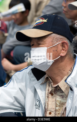 Un vieil homme japonais portant un masque chirurgical de protection pour empêcher la propagation des microbes et de la maladie à des gens autour de lui. Banque D'Images
