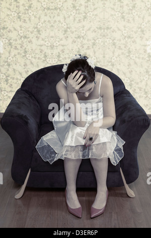 Une femme en robe blanche est assis sur un fauteuil bleu Banque D'Images