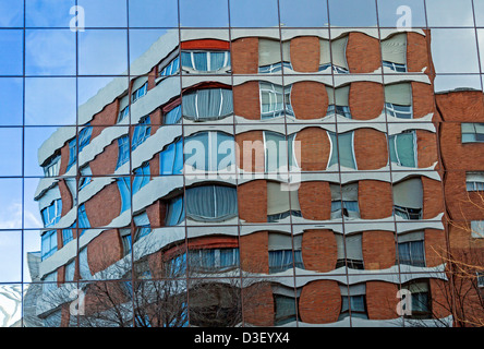Réflexions d'un vieux bâtiment à la façade en verre d'une autre un moderne Banque D'Images
