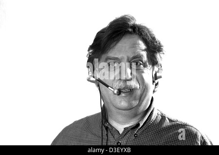 Middle-aged businessman travaille dans les écouteurs avec micro ordinateur derrière, noir et blanc Banque D'Images