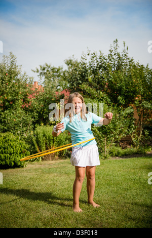 Enfant actif - girl dancing avec arrière-cour ensoleillée à l'extérieur du cerceau Banque D'Images