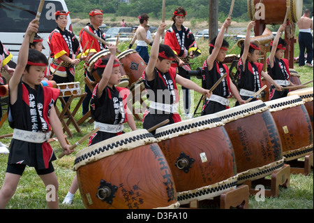 Jeune garçon et fille batteurs dans une tenue de fête garder battre tambours japonais sur un divertissement à fête locale au Japon. Banque D'Images