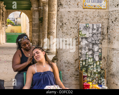 Une jeune femme cubaine dans la vingtaine se fait les cheveux à un salon en plein air par la cathédrale principale de La Havane, Cuba Banque D'Images