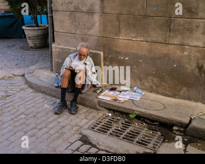 Un vieillard croquis de l'artiste assis sur la bordure d'un trottoir à La Havane, Cuba. Banque D'Images