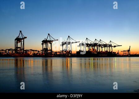 Une vue sur les eaux calmes de l'Elbe vers le terminal à conteneurs d'Hamburg-Altenwerder illuminé et l'grues de chargement s'élevant au-dessus de l'eau dans le soleil du soir à Hambourg, Allemagne 14 juillet 2003. Le terminal est une nouvelle installation qui sera pleinement opérationnel en 2004. Mots-clés : Human-Interest Economy-Business, hum,-Finance, EBF, grues, dominant la rivière, el Banque D'Images