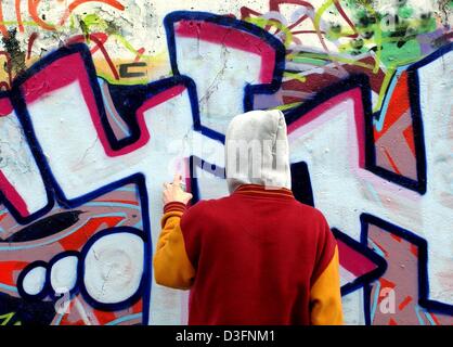 (Afp) - Un jeune homme orne un mur de graffiti art, Frankfurt Oder, Allemagne de l'Est, 11 mars 2003. Les coûts de nettoyage pour les graffitis et le vandalisme, tels que les bris de verre et la démolition des silos, en allemand les gares sont élevés. Dans l'état de Brandebourg seulement, 353 gares ont été touchés en 2002 et 1,5 millions d'euros ont été consacrés aux réparations. Banque D'Images