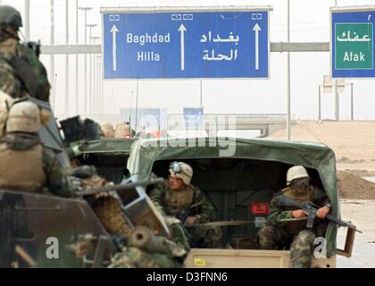 (Afp) - Des US Marines de la 3e (3e Bataillon de Reconnaissance Amoured LAR) se déplacent sur leurs véhicules vers le nord le long de l'autoroute Un et passer sous un panneau routier qui indique la direction vers la capitale irakienne autour de 90 kilomètres au sud de Bagdad, Iraq, 1 avril 2003. Marines américains à se préparer à l'avance décisive sur Bagdad après des jours de repos. Banque D'Images