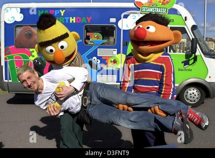 (Afp) - Ernie et Bert, les marionnettes bien connu de la série télévisée 'Sesame Street' porter le joueur de handball national allemand Stefan Kretzschmar en face de la Rue Sésame mini bus, Magdeburg, Allemagne, 13 mars 2003. À l'occasion du 30ème anniversaire de Sesame Street, Ernie et Bert visite des stars sur un bénéfice tour à travers l'Allemagne. Des cadeaux et des dons recueillis au cours de Banque D'Images