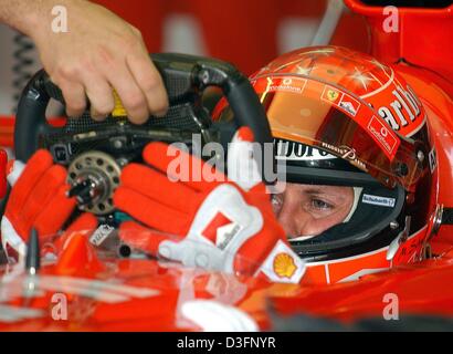 (Afp) - Un mécanicien mains une mulifuntional au volant de formule 1 Allemand Michael Schumacher (Ferrari) de sa voiture de course de formule un Boliden dans le puits de Ferrari sur la piste de course de Formule Un à Kuala Lumpur, Malaisie, 21 mars 2003. Schumacher quitte peu après la fosse pour le cycle de formation gratuit. Le grand prix de formule 1 Course en Malaisie est la deuxième rac Banque D'Images