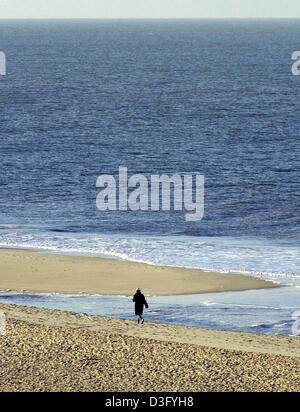 (Afp) - Une femme seule marche rapidement le long de la côte de sable de la mer du Nord par temps clair, à Sylt, Allemagne du nord, 9 février 2003. Banque D'Images