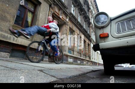 (Afp) - Daniel (L) les chapes d'un trajet sur le guidon de son ami Marko's location à travers les rues du centre-ville de Leipzig, en Allemagne de l'Est, 3 mars 2003. Les garçons passé zip un stationné Trabant, une voiture fabriquée dans l'ancienne Allemagne de l'Est, qui a pris le statut de culte au cours des dernières années. Environ 125 000 Trabants (également appelé Trabis) sont encore sur la route. Banque D'Images