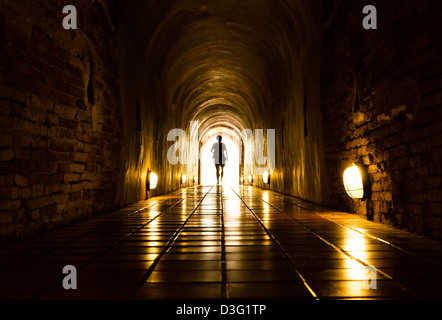 Silhouette d'homme dans l'ancien tunnel en brique à la fin du tunnel de lumière Banque D'Images