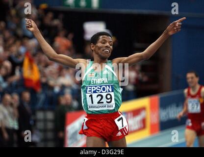 (Afp) - jubilates Éthiopien Haile Gebrselassie, après avoir remporté la finale hommes 3 000 mètres à la 9es Championnats du monde en salle d'athlétisme à la National Indoor Arena (NIA) à Birmingham, le 16 mars 2003. Il prend la première place avec 7:40,97 minutes. Banque D'Images