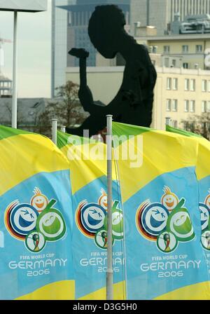 (Afp) - La sculpture 'Hammering Man' est vu derrière les drapeaux de la publicité coupe du monde de football 2006 en Allemagne, à Francfort, 1 décembre 2003. Le tirage pour le groupe de qualification des jeux pour la coupe du monde de football aura lieu à Francfort le 5 décembre 2003. Plus de 900 jeux sont nécessaires pour sélectionner les 31 pays participants de même que le pays hôte de l'Allemagne. Banque D'Images