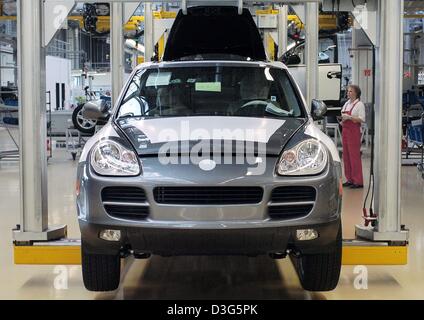 (Afp) - Les employés travaillent sur un Porsche Cayenne à l'usine Porsche à Leipzig, Allemagne, 24 novembre 2003. Un an après son introduction le véhicule tout-terrain sportif a été établie comme étant le modèle phare de Porsche. Le 22 novembre Porsche a publié un prix budget modèle à six cylindres de la Cayenne qui vise à parvenir à un nouveau groupe cible. Banque D'Images