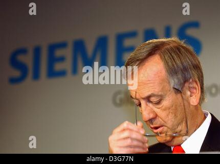 (Afp) - Heinrich von Pierer, Président-directeur général de l'électrotechnologie allemand Siemens géant, enlève ses lunettes au cours de la conférence de presse annuelle de Munich, le 13 novembre 2003. Le bénéfice net de Siemens au cours de l'exercice 2003 a diminué légèrement à 2,44 milliards d'euros, contre 2,6 milliards d'euros l'année précédente. Chiffre d'affaires dans la dernière année a été de 74,2 milliards d'euros, en baisse de 12  % à partir de 2 Banque D'Images