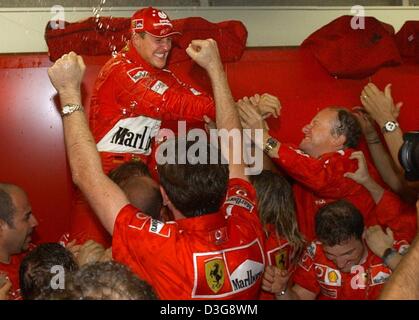 (Afp) - L'Allemand Michael Schumacher, pilote de formule 1 de Ferrari célèbre avec les membres de l'équipe après le clinchage le titre de champion du monde après la formule un Grand Prix du Japon à Suzuka, le 12 octobre 2003. Schumacher placé 8e, remportant un Sixième titre mondial de l'enregistrement. Banque D'Images