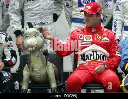 (Afp) - pilote de Formule 1 brésilien Rubens Barrichello (Ferrari) choisit l'oreille d'un âne gonflable qui se trouve sur le siège de l'allemand champion du monde de Formule 1 Michael Schumacher (Ferrari) qui est en retard pour une photo de groupe avant le début de la Formule Un Grand Prix du Brésil à Interlagos le circuit dans Sao Paulo, Brésil, 24 octobre 2004. Banque D'Images