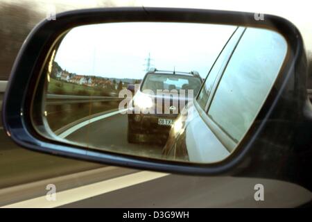 (Afp) - une voiture qui suit clignoter ses phares demande à un automobiliste de conduire plus vite, vu la voiture dans un rétroviseur dans une scène sur une route près de Lichtenfels, Allemagne, 6 février 2004. Près de la moitié des conducteurs d'autoroute risquent des accidents en roulant trop près de la voiture de devant, un rapport met en garde. Le talonnage agressif, tels que les lumières clignotantes et des gestes agressifs, également bec Banque D'Images