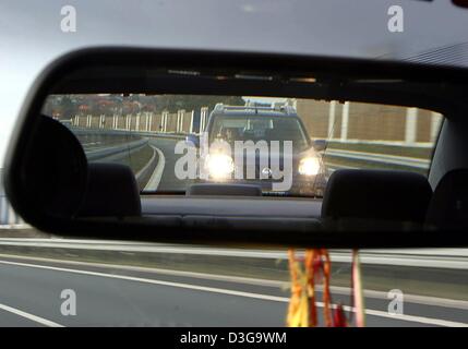 (Afp) - une voiture qui suit clignoter ses phares demande à un automobiliste de conduire plus vite, vu la voiture dans un rétroviseur dans une scène sur une route près de Lichtenfels, Allemagne, 6 février 2004. Près de la moitié des conducteurs d'autoroute risquent des accidents en roulant trop près de la voiture de devant, un rapport met en garde. Le talonnage agressif, tels que les lumières clignotantes et des gestes agressifs, également bec Banque D'Images