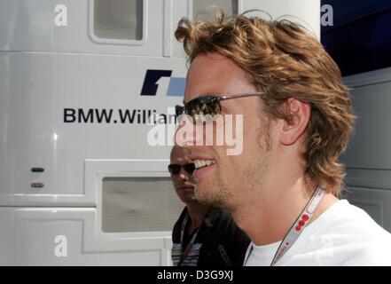 (Dpa) - pilote de Formule 1 britannique Jenson Button (BAR-Honda) de l'équipe passe devant le camping-car de l'équipe BMW-Williams dans le paddock de course sur le Hungaroring, près de Budapest, Hongrie, 12 août 2004. Bouton qui avait l'intention de changer les équipes et prévu de conduire pour BMW-Williams en 2005 demeurera à BAR-Honda pour une autre saison après la reconnaissance des contrats de Formule Un a décidé e Banque D'Images