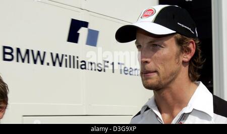 (Dpa) - pilote de Formule 1 britannique Jenson Button (BAR-Honda) de l'équipe passe devant le camping-car de l'équipe BMW-Williams dans le paddock de course sur le Hungaroring, près de Budapest, Hongrie, 12 août 2004. Bouton qui avait l'intention de changer les équipes et prévu de conduire pour BMW-Williams en 2005 demeurera à BAR-Honda pour une autre saison après la reconnaissance des contrats de Formule Un a décidé e Banque D'Images