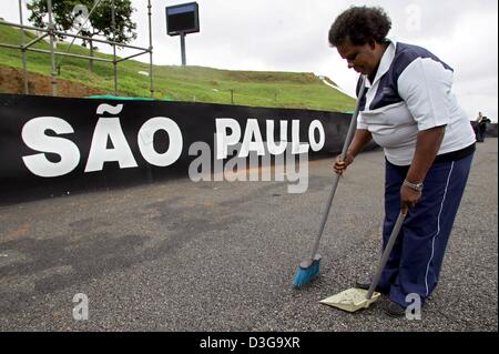 (Afp) - le personnel de nettoyage Balayer une partie de la piste de course de formule 1 de l'Interlagos, près de Sao Paulo, Brésil, 20 octobre 2004. Le Grand Prix du Brésil a lieu ici le dimanche. Banque D'Images