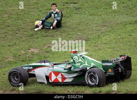 (Afp) - Le pilote de Formule 1 Mark Webber s'assoit à côté de sa Jaguar après qu'il s'est écrasé sur la course pendant la Formule Un Grand Prix du Brésil à Interlagos le circuit dans Sao Paulo, Brésil, 24 octobre 2004. Banque D'Images