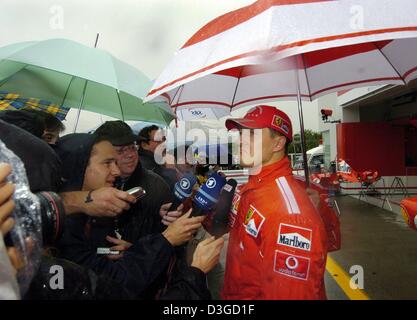 (Afp) - L'Allemand pilote de Formule 1 Michael Schumacher (Ferrari) de l'équipe fait une grimace qu'il donne une interview après la fin de la formation gratuite à Suzuka International Racing course à Suzuka, Japon, 8 octobre 2004. En raison de l'approche d'un typhon, course pourrait être annulé le samedi et peut-être même le dimanche. Le Grand Prix du Japon aura lieu le dimanche 10 octobre 2004. Banque D'Images