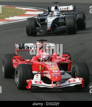 (Afp) - pilote de Formule 1 brésilien Rubens Barrichello (Ferrari) L'équipe est suivie de près par la Finlande, l'équipe de Kimi Raeikkoenen (McLaren-Mercedes) sur son chemin pour gagner le Grand Prix de Chine sur le nouveau Circuit International de Shanghai à Shanghai, Chine, le 26 septembre 2004. Le pilote britannique Jenson Button (BAR-Honda) est arrivé en deuxième position avec Raeikkoenen terminant troisième. Banque D'Images