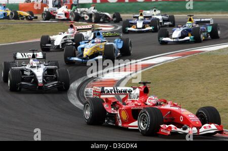 (Afp) - pilote de Formule 1 brésilien Rubens Barrichello (Ferrari) de l'équipe mène le pack au début du Grand Prix de Chine sur le nouveau Circuit International de Shanghai à Shanghai, Chine, le 26 septembre 2004. Barrichello a remporté le Grand Prix britannique, Jenson Button (BAR-Honda) est arrivé en deuxième position avec Raeikkoenen terminant troisième. Banque D'Images